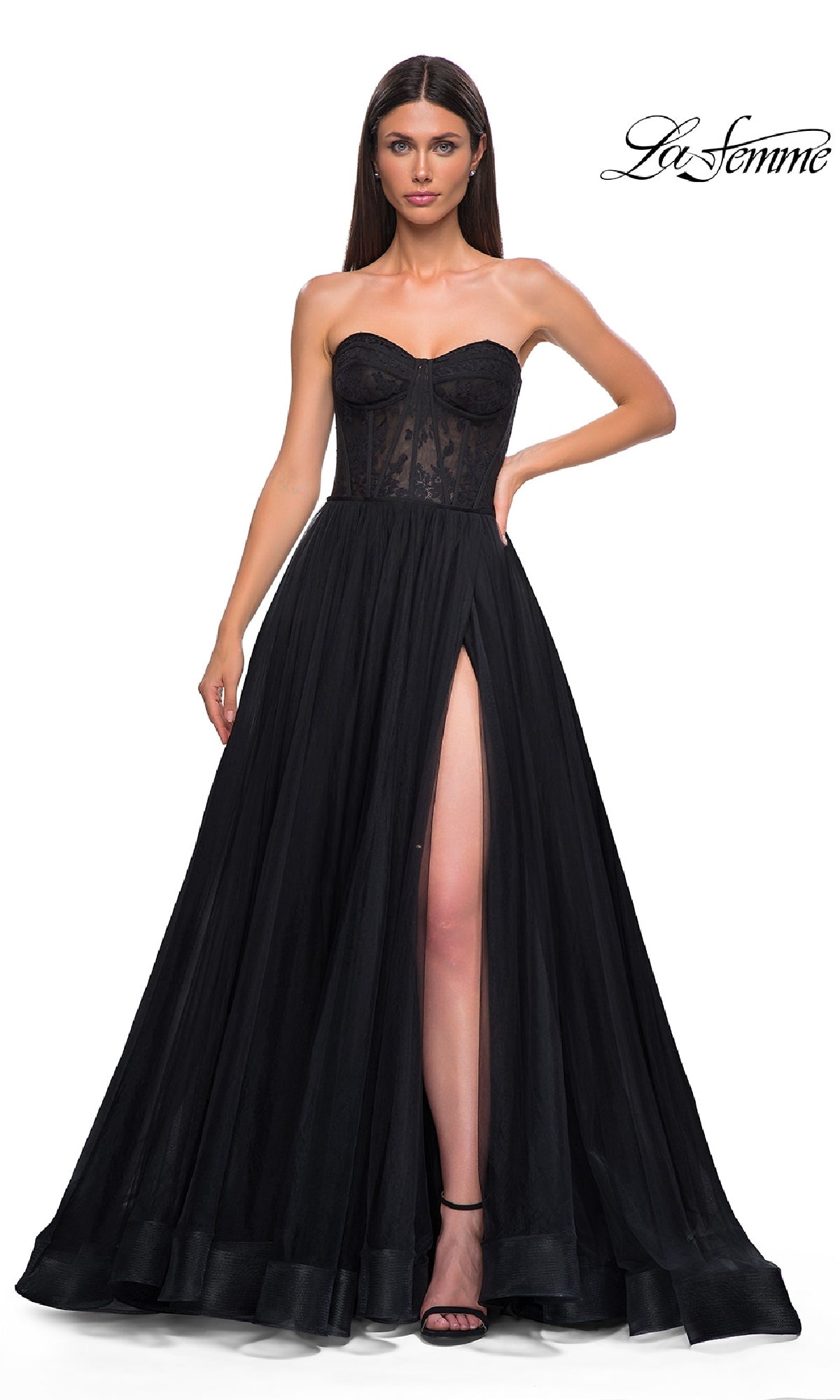 A woman in the La Femme 32579 Strapless Long Prom Ball Gown with a floral corset bodice and high slit stands against a plain white background.
